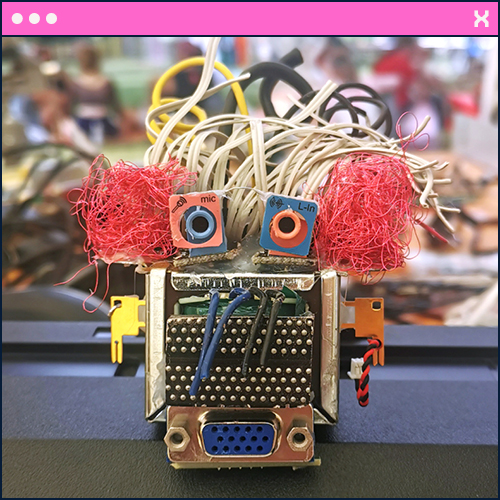 Foto im Retro-Browserstil: Nahaufnahme einer kleinen Roboterfigur mit Klinkenbuchsen als Augen und dünnen Datenkabeln als Haare.